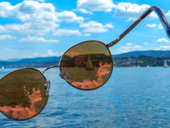 Close-up of sunglasses on sea against sky