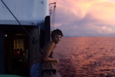 Portrait of young woman in ferry on sea during sunset
