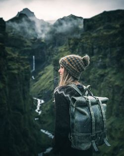 Woman looking away while standing against mountain and sky