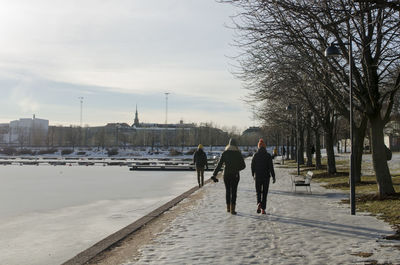 Rear view of people walking on snow covered road