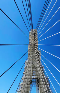 Low angle view of suspension bridge against clear blue sky