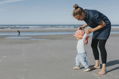 Netherlands, schiermonnikoog, mother walking with little daughter on the beach