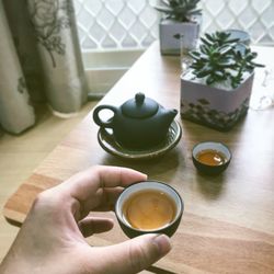 Cropped hands of woman holding coffee on table