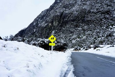 Road by snow covered mountain against sky