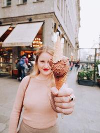 Portrait of woman holding ice cream in city