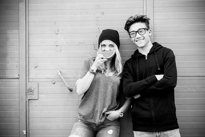 Portrait of young couple standing against wall