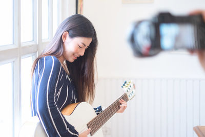 Full length of young woman playing guitar