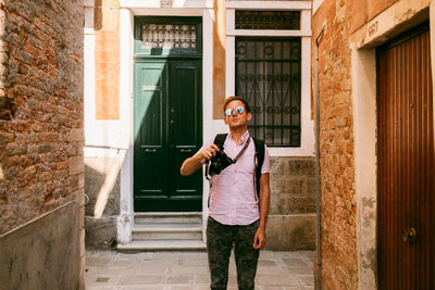 Full length of man wearing sunglasses standing against building