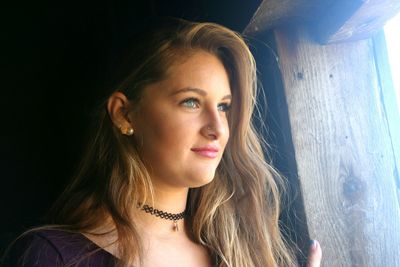 Thoughtful smiling woman looking through wooden window