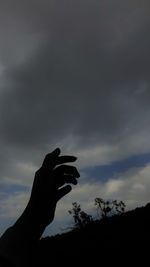 Silhouette person holding umbrella against sky during sunset