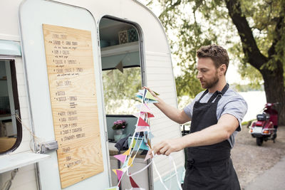 Male owner holding bunting flags outside food truck