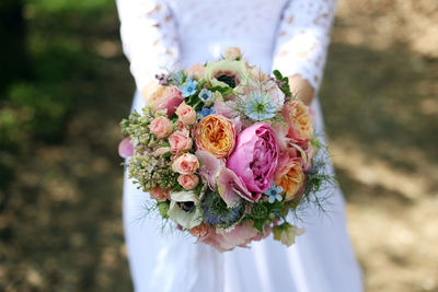 Close-up of bride holding bouquet standing outdoors