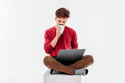 Young man using smart phone against white background