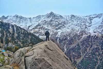 Man standing on big rock object on mountain against sky