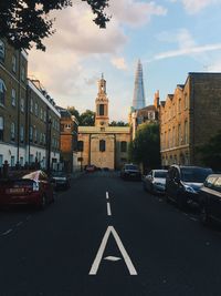 Road amidst buildings in city against sky