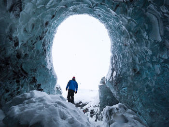 Rear view of man walking on snowcapped mountain