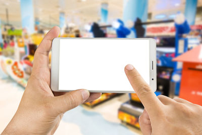 Cropped hands of man using smart phone in store