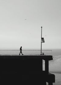 Man on pier at beach against sky