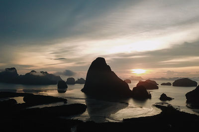 Scenic view of rocks in sea against sky during sunset