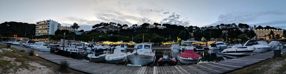Panoramic view of boats moored in city against sky