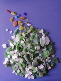 Close-up of small pieces of glass polished by the sea on a blue table 