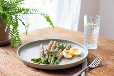 Fresh asparagus wrapped in bacon and grilled, served with egg benedict. healthy food.