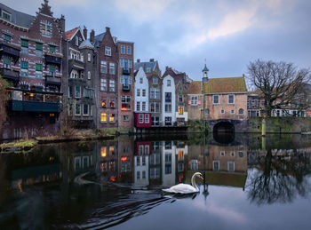 Buildings by river against sky