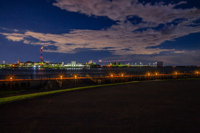 Illuminated city by river against sky at night