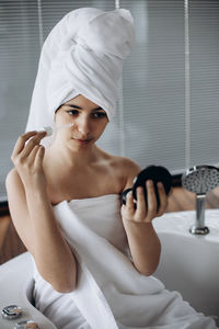 Low angle view of young woman sitting on bed at home