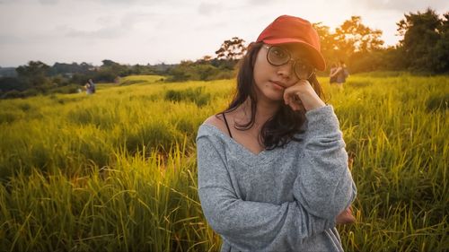 Beautiful woman standing on field against sky