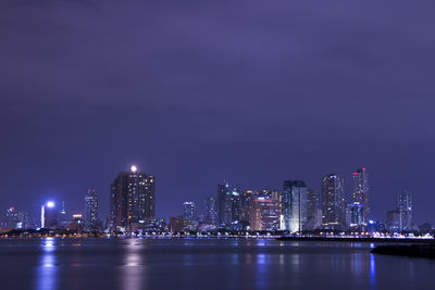 Illuminated city buildings against sky at night