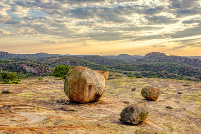 Hay bales on rock against sky during sunset