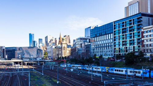 Railroad tracks amidst buildings in city against sky