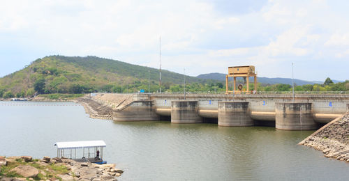 Built structure by river against sky