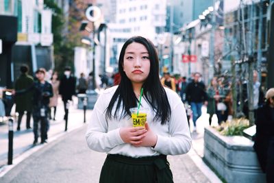 Portrait of young woman standing in city