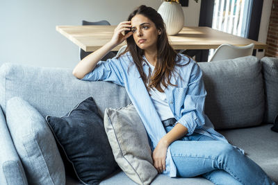 Young woman sitting on sofa at home