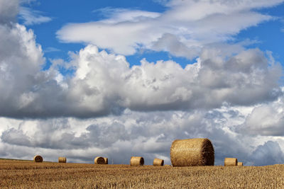 Hay bales on field against sky