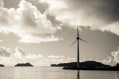 Wind turbine in water against sky