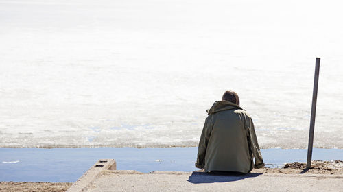 Rear view of woman sitting on beach