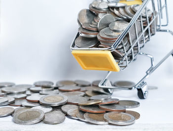 High angle view of coins and shopping cart on gray background