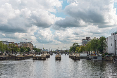 Buildings by river against sky