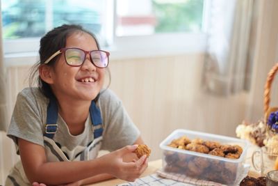 Cute smiling girl eating food while sitting at home