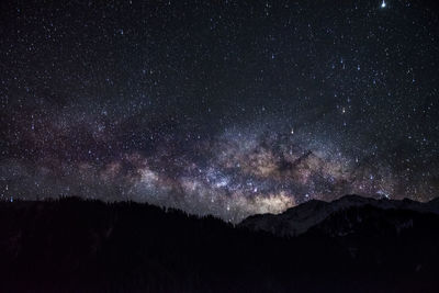 Scenic view of silhouette mountains against star field at night