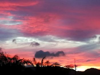 Low angle view of silhouette trees against dramatic sky