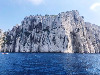 Scenic view of sea by mountain against sky