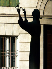 Side view of silhouette woman standing against building