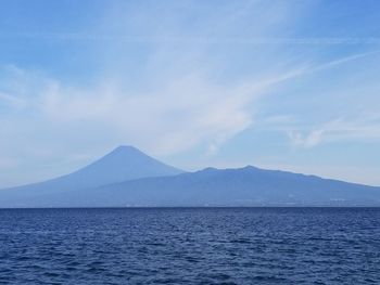 Scenic view of sea by mountains against sky