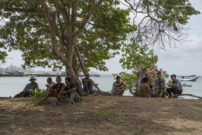 Group of people sitting on ground by tree