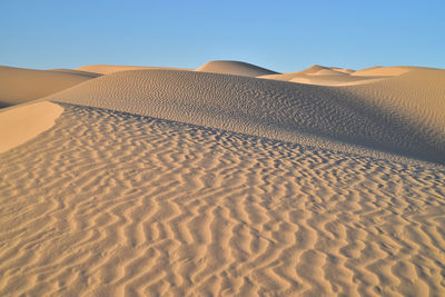 Sand dunes in desert against clear sky