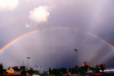 Rainbow over trees against cloudy sky